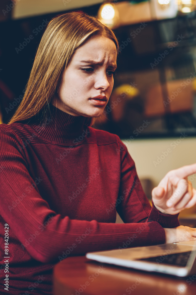 Poster thoughtful woman puzzled on received email from work pointing on laptop screen while spending time i