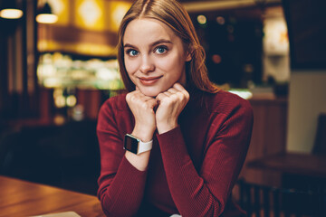Happy female student looking at camera after planning time for course work in textbook, portrait of successful remote worker sitting in cafeteria with modern netbook using free internet connection