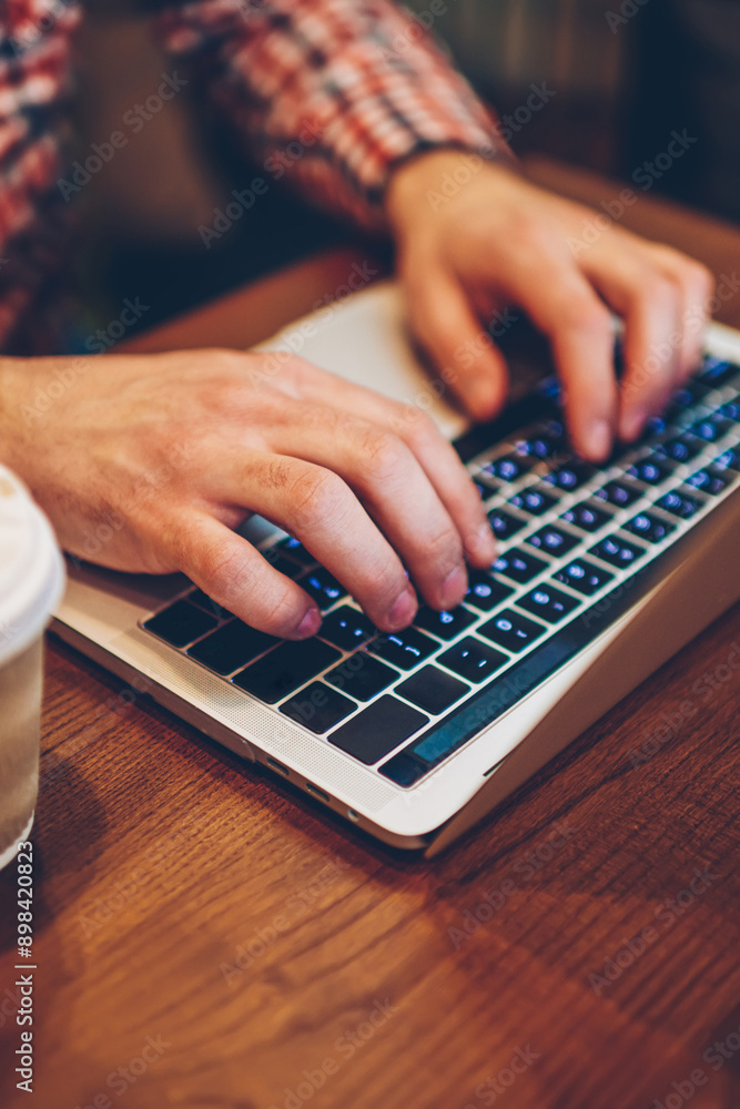 Poster cropped image of male hands typing information for website via keyboard on laptop computer connected