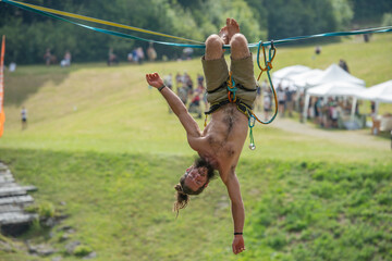Tightrope walker walking on rope suspended from ground in park