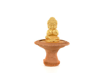 A small Buddha statue sits on a pottery base.