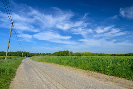Petite route de campagne dans un paysage normand avec ciel et champ au grand angle