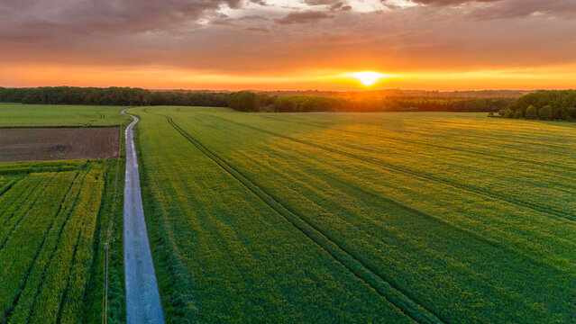 Vue a&eacute;rienne du coucher de soleil sur fond dramatique tr&egrave;s nuageux et orageux au milieu des champs et des for&ecirc;ts du bocage normand en France