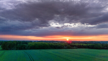 Vue aérienne du coucher de soleil sur fond dramatique très nuageux et orageux au milieu des champs et des forêts du bocage normand en France