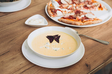 Cheese cream soup and pizza in the home kitchen, homemade food for family lunch.