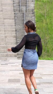 Vertical full length video of a latin sensual young woman opening arms dancing cuban salsa in a park