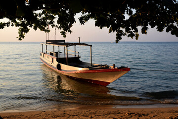 Fototapeta premium Boats on the edge of a clean beach, the rays of the setting sun