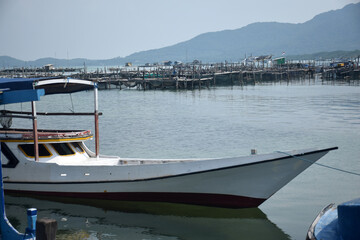 Fototapeta premium The boat is moored at the edge of the clean pier and the sea water is sparkling.
