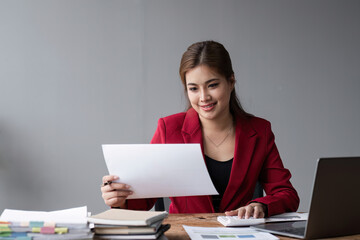 Young Accountant Analyzing Financial Documents in Modern Office Setting with Laptop and Paperwork