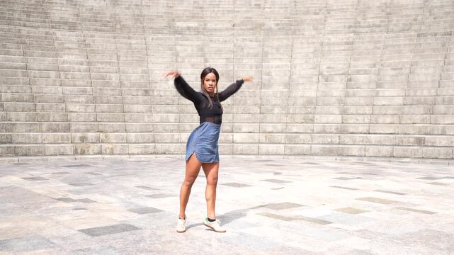Latin beauty sensual woman raising hands dancing salsa alone in a city