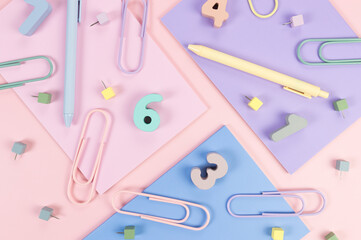 Top view of pink, purple and blue notebooks on pink background. Colorful pens, paperclips, numbers and pins. School, office wallpaper. Flat lay, copy space.