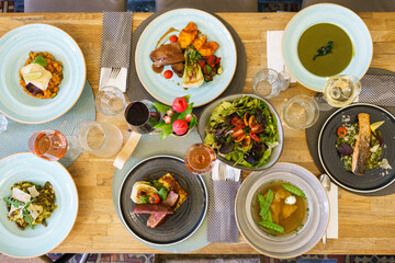 High angle view of a restaurant dining table with variety of gourmet dishes and fine wines
