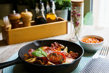 English Breakfast in cooking pan with fried eggs, sausages, bacon, mushrooms, beans and tomato