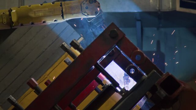 No people side shot of automatic robotic arm welding red and yellow machinery framework in tractor production factory, implementing computer-aided operations at work