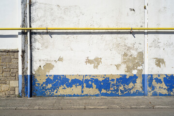 Tubería amarilla en pared grande de vieja fábrica blanca y azul