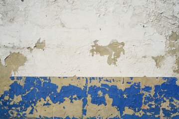 Pintura azul desconchada en pared blanca de edificio grande en calle