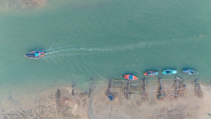 Aerial view of fisherman's boat was moored along the shore, and a boat was moving in the sea on the blue water surface.