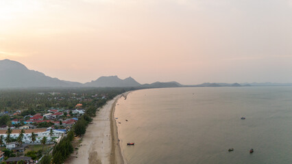 Aerial view of beautiful beach in morning, golden sky and mountains background.