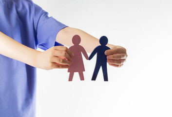 The girl holds figurines of her mother and father in her hands. Orphans concept. Adoption of...