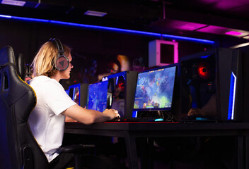 Gamer plays PvP shooter battle royale video game on PC at computer club. Skill. Professional modern headset, keyboard with RGB light, gaming equipment. Cyber sport tournament Esports championship