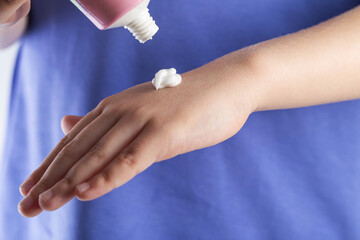 The hands of a girl apply a medicinal cream against chapping of the skin on a white background. Moisturizing and protective hand cream, close-up