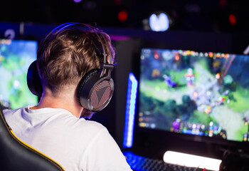 E-sport tournament Gamer in headset plays video game on PC Computer club, real-time strategy RTS multiplayer online battle competition. Skill. Gaming earphones. Professional cyber sport championship © HENADZY