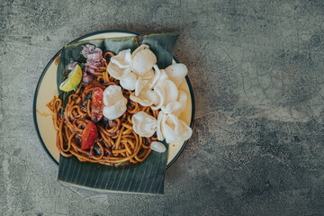 Mie Aceh. Stir-fried spicy noodles from Aceh, Indonesia. Flat lay, overhead, or top view angle with the object on the left side.