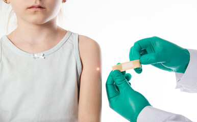 The hands of a doctor in green medical gloves hold a medical plaster against the background of a...