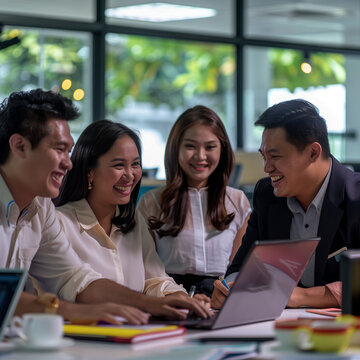 a group of people are sitting around a laptop and one of them is on a laptop