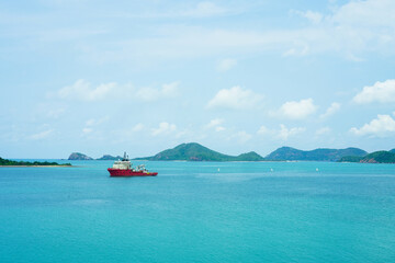 A scenic view of a tourists boat sailing in the sea with green trees on the mountain against blue...