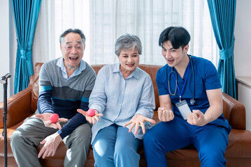 young male assistant in uniform advice asian senior couple exercise hands with a ball,home health care nurse visit asian senior family at home,concept elderly health care,homecare,home health nursing