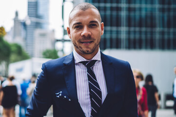 Portrait of handsome businessman dressed in formal wear looking at camera spending free time in modern city.Successful entrepreneur in expensive elegant suit standing on street of downtown