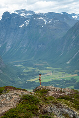 male backpacking hiker with yellow backpack climbing Romsdalseggen trail in Andalsnes Norway in summer with rocky mountains in the background