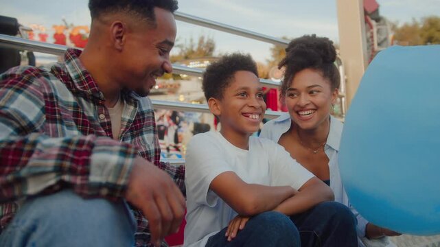 Cute boy sitting between mom and dad and laughing friendly