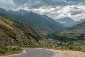 Road in a mountain gorge and a stormy sky. Traveling in Kyrgyzstan