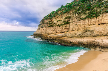 dramatic landscape of white sand beach with golden rocks and stones with beautiful rock cliff , sea surf and nice dramatic blue cloudy sky