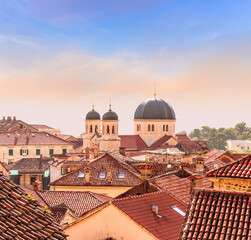 Fototapeta premium beautiful old city sunset landscape with ren and orange tile roofs of houses and nice cathedral church in traditional venetian style with bell tower and chapel and evening sky on background