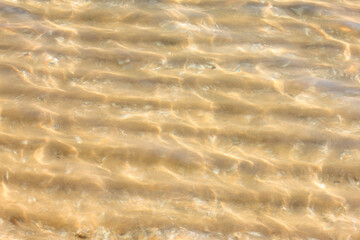 The clear, shallow water of Lake Michigan shows the rippled sand beneath it just off the beach at Harrington Beach State Park, Belgium, Wisconsin, as the sun dances off the water's surface