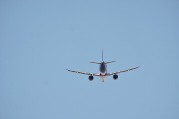 Airplane in Flight Viewed from Behind Against Clear Sky