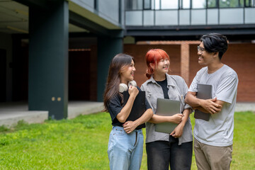 Three young people are standing in a grassy area, smiling and holding backpacks