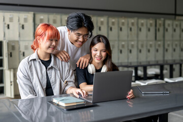 Three people are sitting at a table looking at a laptop