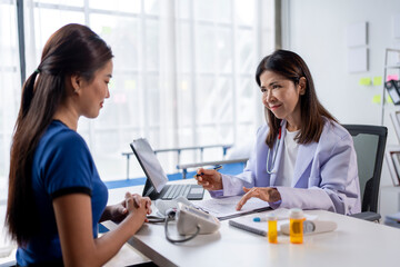 A woman is sitting at a desk with a doctor