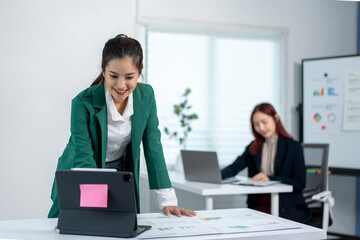 Fototapeta premium A woman in a green jacket is standing in front of a white board with a pink note