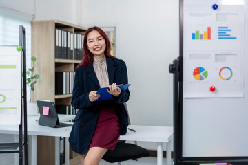 A woman in a business suit stands in front of a white board with a blue clip in