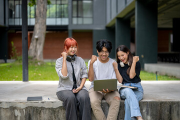 Obraz premium Three young people are sitting on a cement ledge, one of them holding a laptop