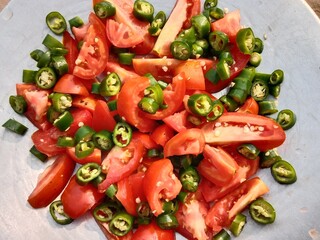 Sliced tomatoes with Chopped green chili pepper in a top.Cutted tomato piece with cutted green chillies pattern background 