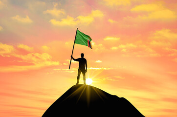 Waving flag of Zambia at the top of a mountain summit against sunset or sunrise. Zambia flag for...