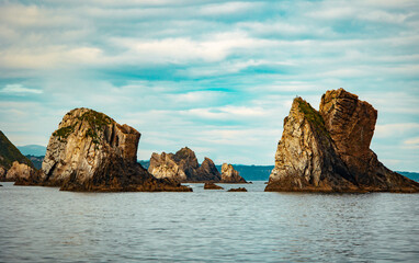Fototapeta premium Majestic sea stacks rising from calm ocean water under a cloudy sky