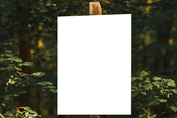 Empty white sign on wood post in green forest for text