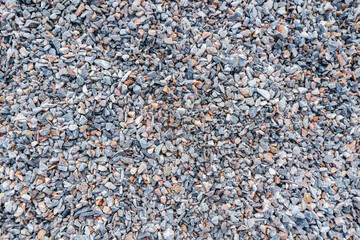 Bulk of crushed rock or pebble rock, material for house building, that placed on the construction work site. Top view close-up, selective focus.